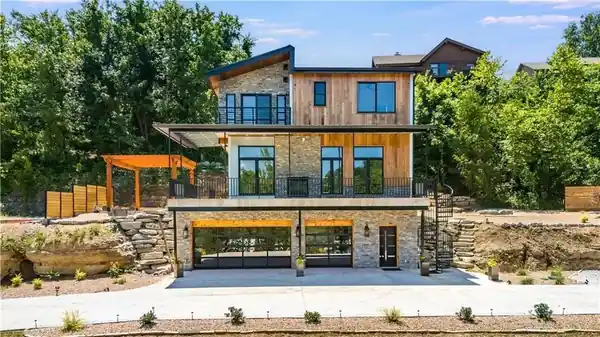 Modern stone and cedar house with full-view glass garage doors at the lower level