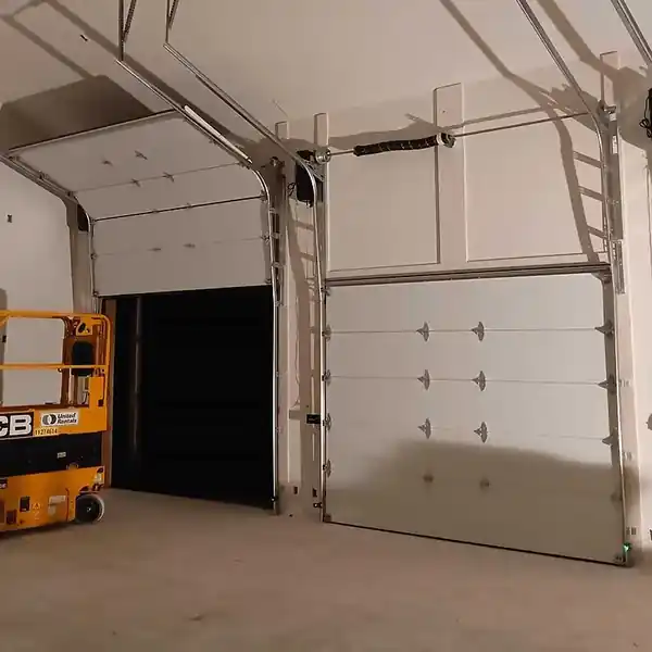 Two new sectional garage doors installed with a scissor lift in front of a new shop