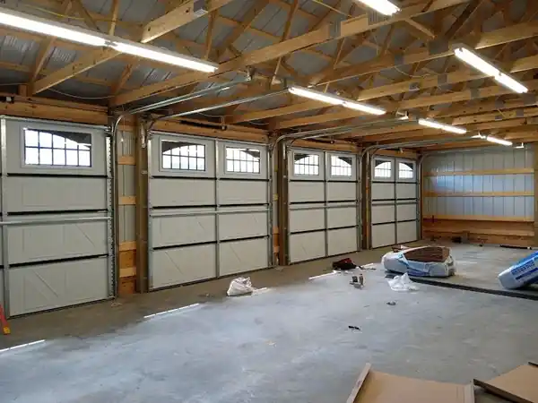 Pole-barn interior with four white windowed overhead doors