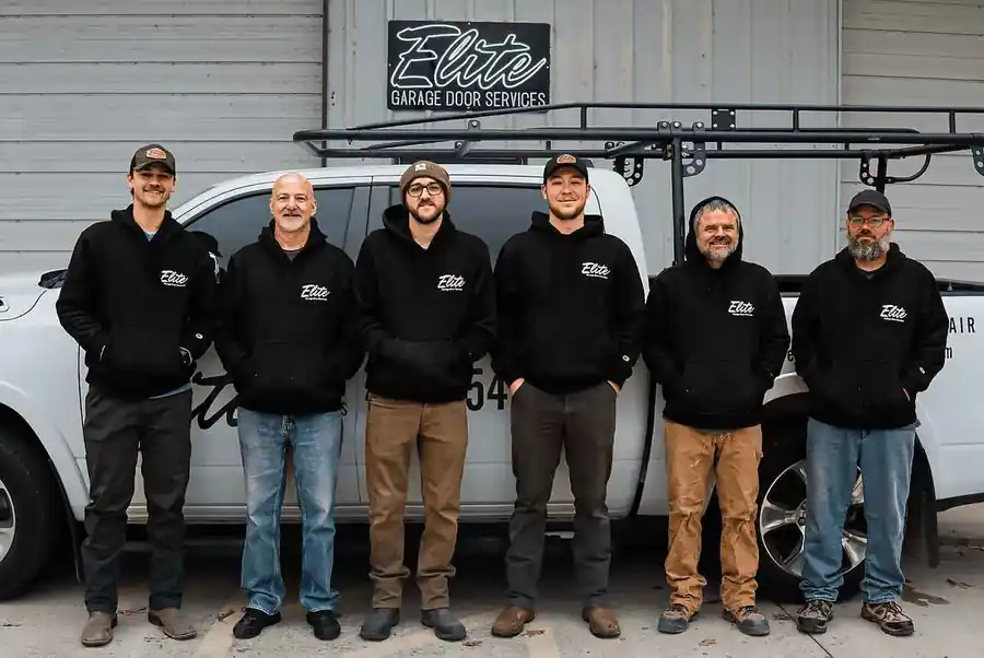 The Elite Garage Door Services crew in company hoodies outside the shop, under the Elite sign