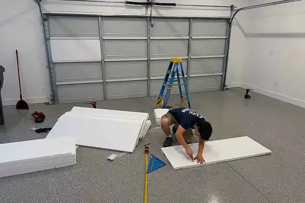 An Elite technician cutting insulation panels at the workbench for a garage door section