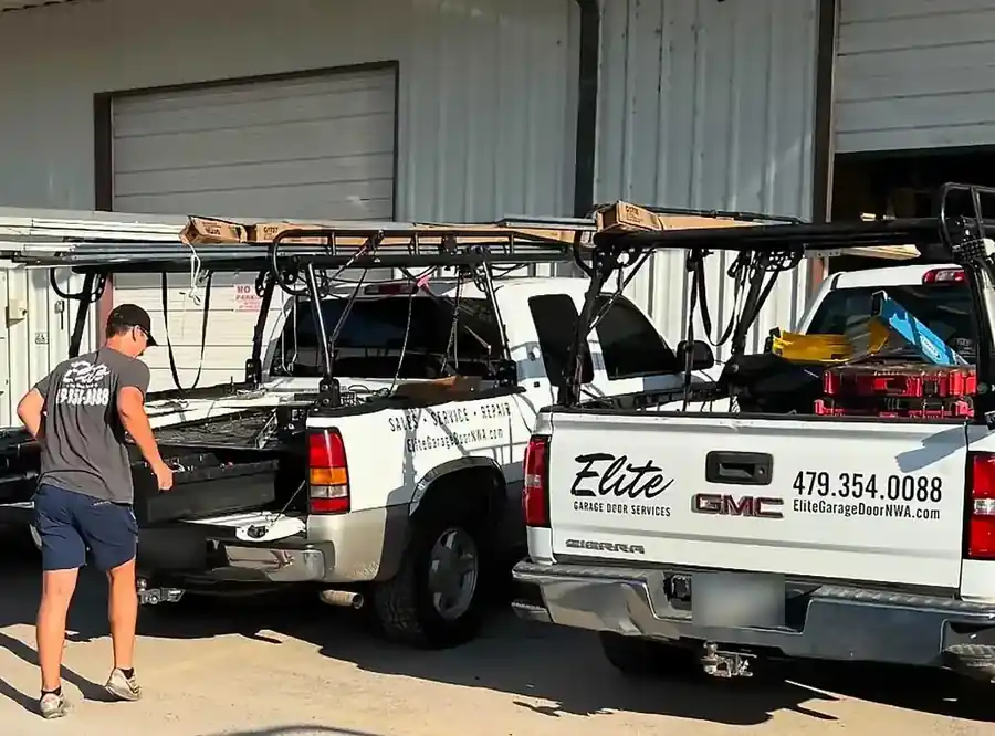 Two Elite Garage Door Services pickups with ladder racks, the tailgate lettered with 479.354.0088